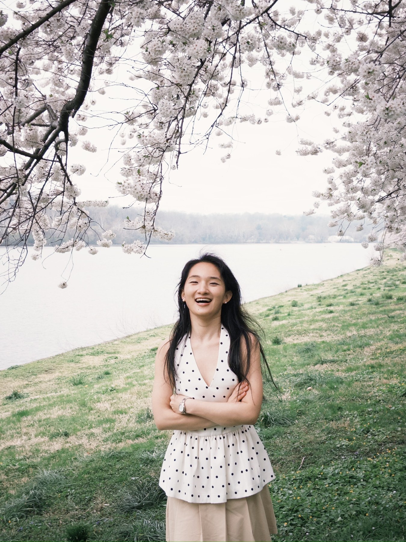 Jie Grace Li smiling beneath spring blossoms in a park